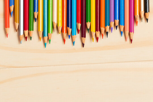 LAPICES LARGOS DE MADERA DE VARIOS COLORES, SOBRE MESA DE MADERA CLARA. FOTOGRAFIA HORIZONTAL. COLOR.  
