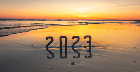 Fototapeta Bonne année 2023 : concept de nouvelle année 2023 avec un lever de soleil sur la plage et les chiffres 2023 en reflet dans la mer. obraz