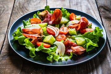 Tasty salad - prosciutto crudo and fresh vegetables on wooden table
