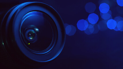 Camera lens in blue light close-up, lights out of focus on the background