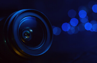 Camera lens in blue light close-up, lights out of focus on the background