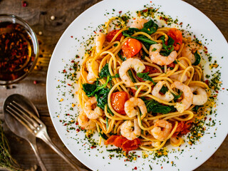 Spaghetti with prawns and spinach on wooden table