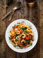 Spaghetti with prawns and spinach on wooden table