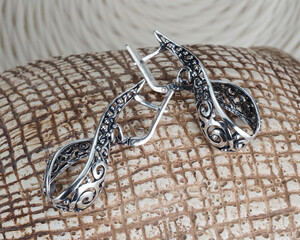 a set of jewelry from a ring and earrings with zircon on an artistic curly background