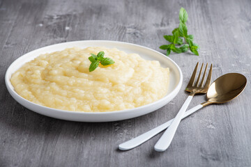Mashed potatoes in white plate on gray wooden background