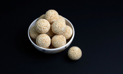 Makar Sankranti festival, pile or stacked The indian sesame sweet Rajgira laddu made from Amaranth seed in Bowl black background
