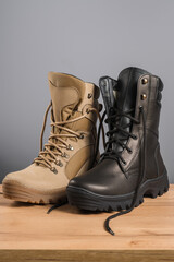 Khaki and black tall military boots on a gray background