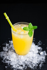 Glass of fresh orange juice with ice on a black background with a place for inscription