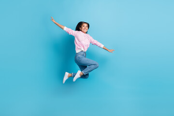 Fototapeta na wymiar Full length photo of sweet cute girl dressed pink pullover jumping high arms sides isolated blue color background