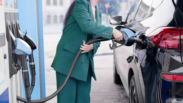 business woman refuels a car at a gas station. A woman fills a diesel engine with gasoline in a car using a fuel injector.