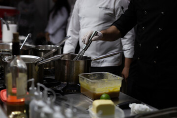 A cook stirring pots in the kitchen. Big pots in the kitchen