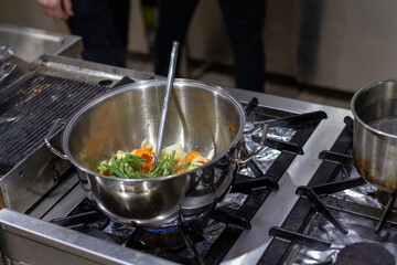 Vegetables in pots in the kitchen. Steel pots