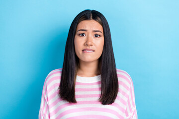 Photo of doubtful unsure young lady wear striped sweater biting lip isolated blue color background