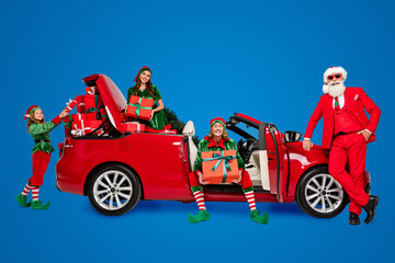 Photo of funny positive santa claus assistants wear costumes riding red transport delivering...