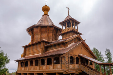 Christian orthodox wooden church with gold domes and crosses. Calm grey sky above