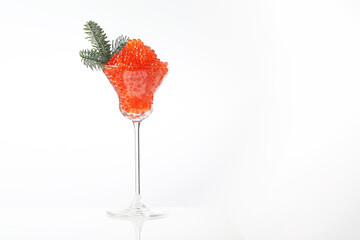 Caviar, a glass wine glass filled with red caviar. White background. Salmon caviar. Delicacies. Delicious food. Concept of delicious food. Space for text.Spruce branch.
