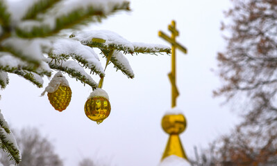 A branch of a Christmas tree with decorations on the background of an Orthodox cross with a crucifix. The Orthodox Church. Winter is Christmas. The concept of Orthodoxy.
