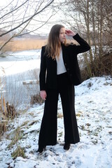 Young girl in black elegance wear walk in the winter forest. Sunset and snow	