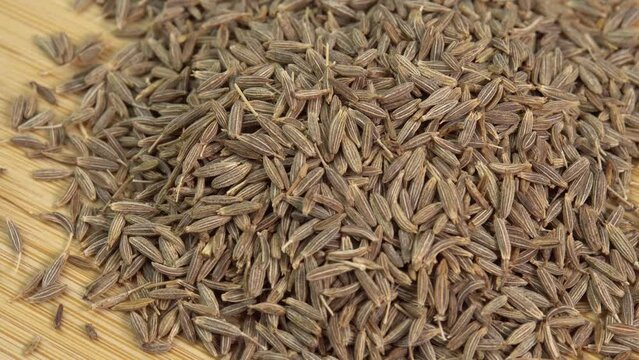 Dried cumin spice seeds rotate on wooden background. Dry seasoning cumin. Spices and herbs for cooking zira