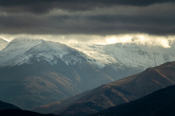 Stormy clouds with sunbeams over snowy mountains in Granada (Spain)