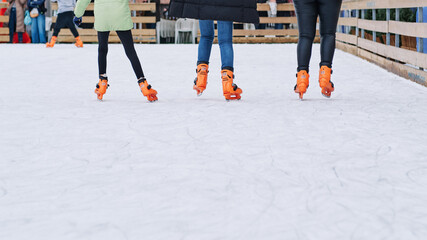 Three women of different ages skating together on an urban ice rink.