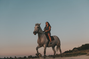 portrait of a long-haired girl on a horse in the sea on a sandy beach