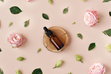 Wooden podium with amber glass dropper bottle on trendy pastel beige background with flower buds, leaves, petals. Abstract cosmetics composition with roses. Beauty layout. Summer, aroma water concept