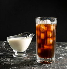 Iced coffee and milk in a milk jug on a black background