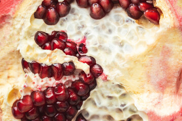 Half of fresh pomegranate fruit as a textured background. Ripe pomegranate cracked in a half with...