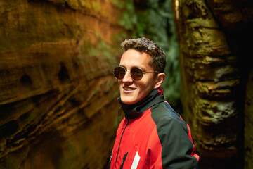 A shallow focus shot of handsome young Hispanic boy with sunglasses and coat posing in nature