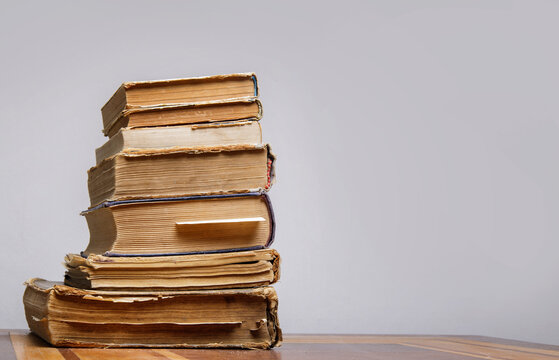 on a wooden table on a gray background a stack of old books with bookmarks. High quality photo