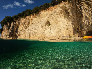 Fototapeta premium Underwater split photo of sport canoe anchored in tropical exotic island pebble beach with crystal clear turquoise sea forming a blue lagoon