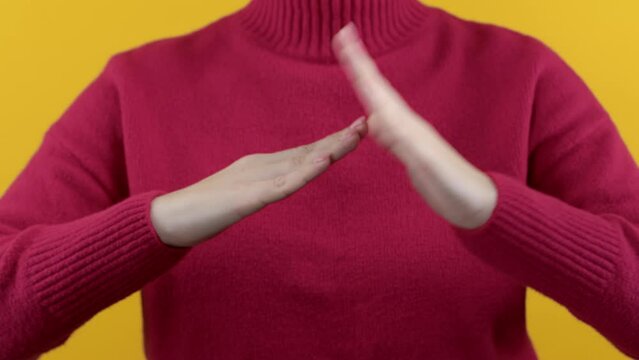 Hands showing timeout gesture, limit, stop, time break on yellow red studio background. Woman with signal of pause, no, enough