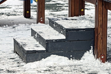 black threshold with wooden steps in white snow on a winter street