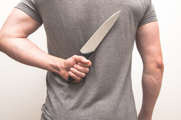 Man holding a kitchen knife behind his back.