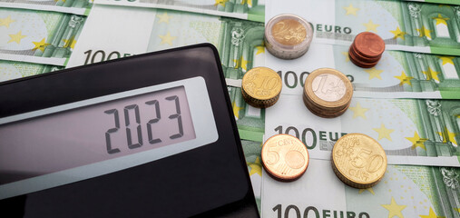 New financial year 2023. Calculator on the background of banknotes of 100 euros. The concept of rising cost of electricity, inflation and high cost of living in the New Year 2023