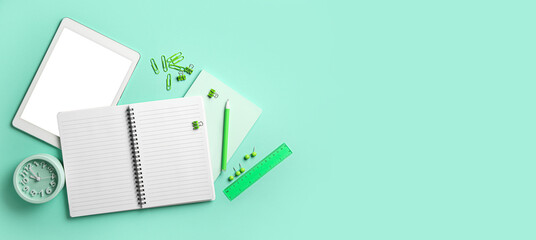Blank notebook, alarm clock, tablet computer and stationery on turquoise background with space for...