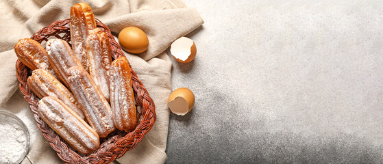Basket with sweet eclairs on light background with space for text, top view