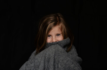 Little girl in a sweater on a black background