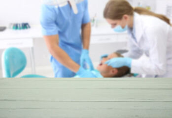 Obraz premium Empty wooden table and dentist examining little boy's teeth in clinic