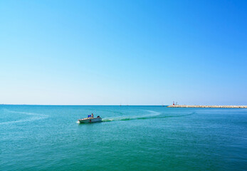 Adriatic sea, waves, boat with people and landscape. Rimini, Italy.