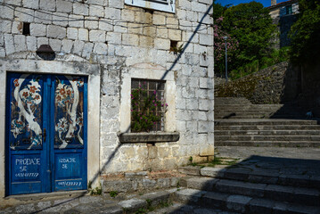 Facade of an old house. Mediterranean building. Steps up. Blue door. Textured stonework.