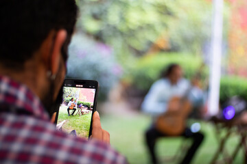 latin man recording with a smartphone a classical guitarrist guitar player playing spanis guitar in...