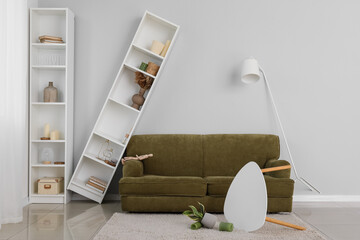 Interior of messy living room with green sofa, shelving units and lamp