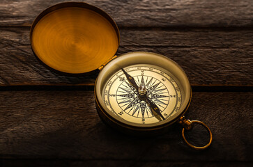 Fototapeta na wymiar Golden compass on dark wooden background
