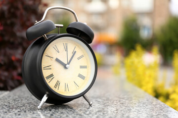 Black vintage alarm clock in park, closeup