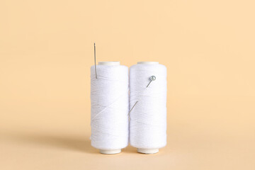 White thread spools with ball pin and needle on color background