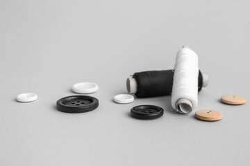 Fototapeta na wymiar Thread spools with buttons on grey background
