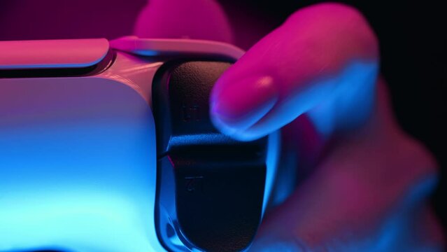 Gamer's hands playing online video game on console TV with joystick, neon color light. Woman presses buttons, using joypad controller, newest wireless gamepad. Hobby, e-sport, macro view