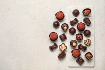Board with chocolate candies on white background